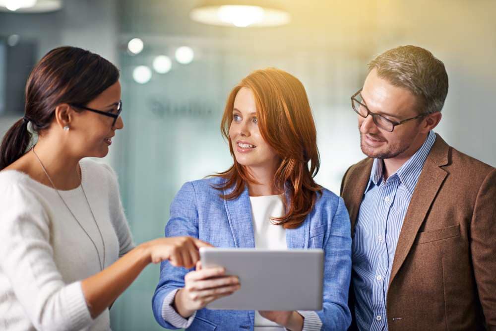 Three business people discussing using tablet