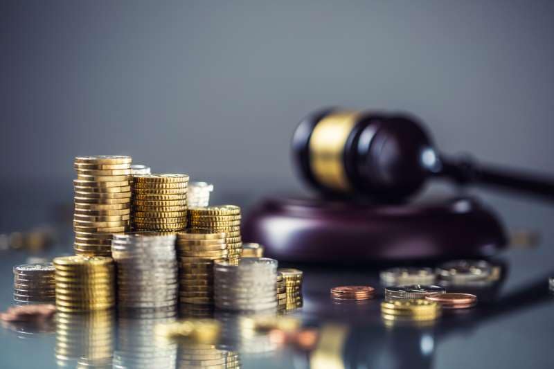 Stacks of coins with legal gavel in background
